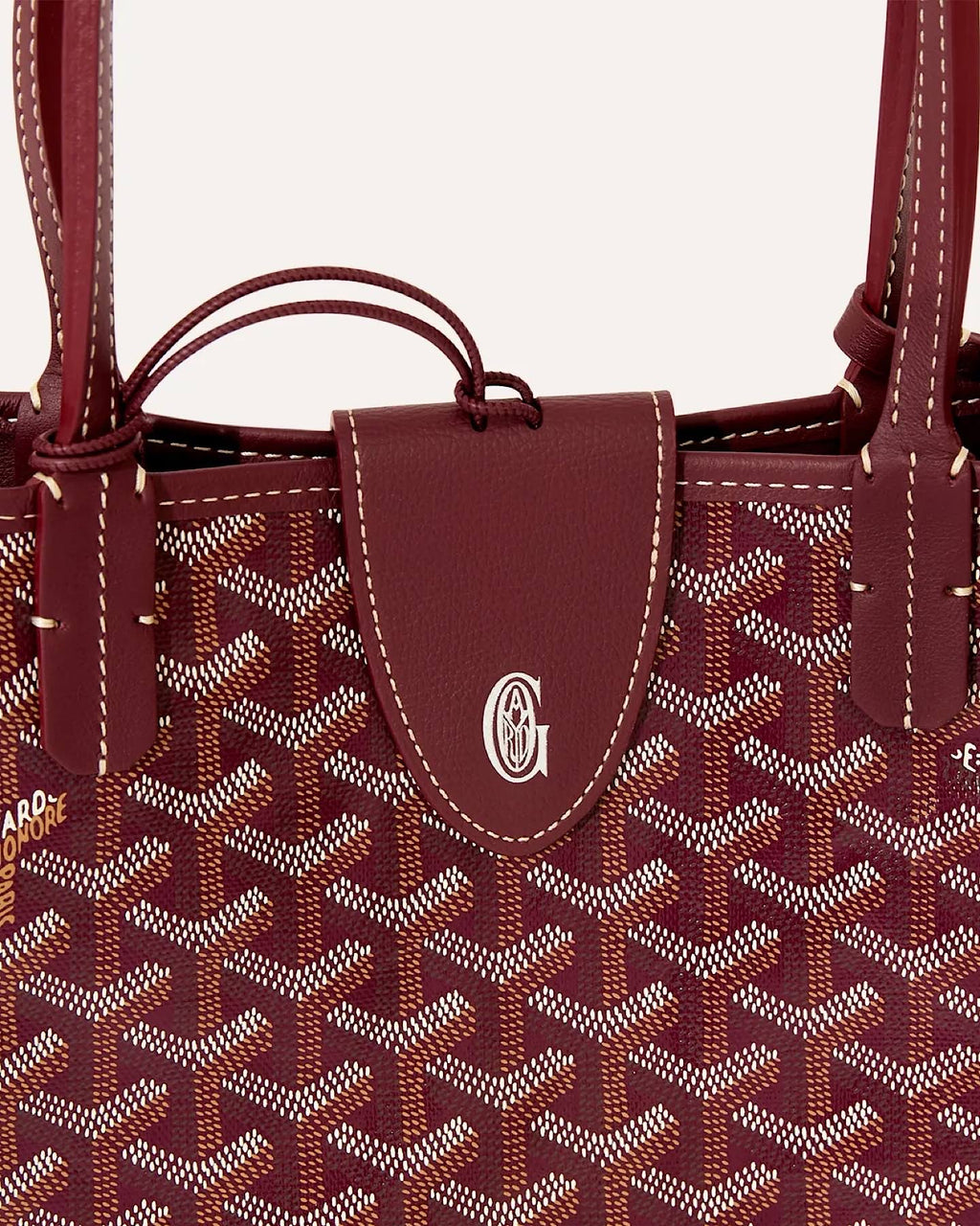 Close-up of Goyard Sac Anjou Mini featuring burgundy Goyardine canvas, leather trim and signature front tab detail.